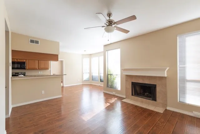 a view of a kitchen with a ceiling fan a fireplace and wooden floor