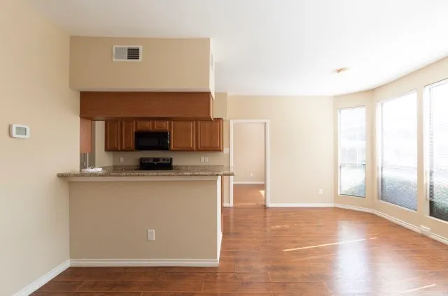 a living room with stainless steel appliances a fireplace a flat screen tv and a window