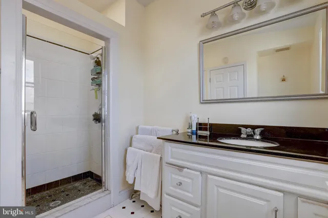 a bathroom with a granite countertop sink a mirror and shower