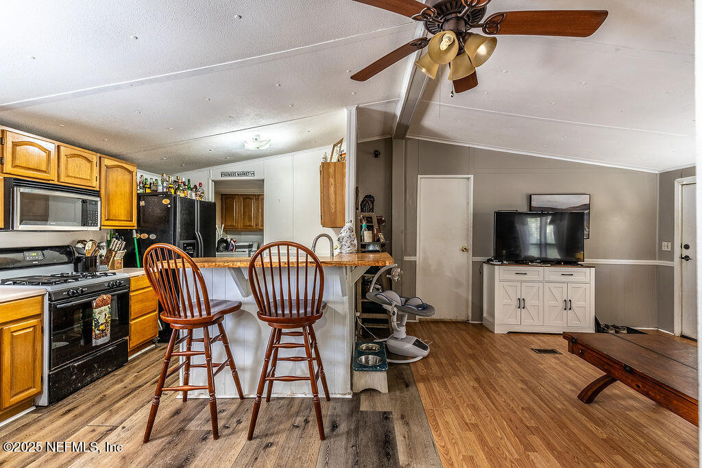19040 Waterville Road Jacksonville, FL 32226 - Photo 10 of 28 a kitchen with stainless steel appliances granite countertop a stove a refrigerator a sink a dining table and chairs with wooden floor