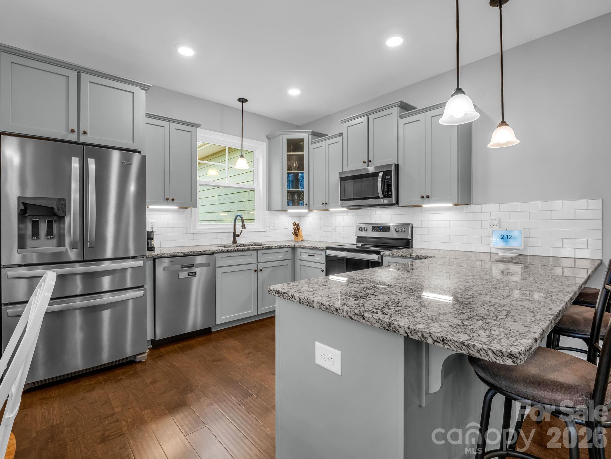 631 Mountain Parkway Mill Spring, NC 28756 - Photo 12 of 43 a kitchen with granite countertop a stove a sink a microwave a refrigerator and white cabinets