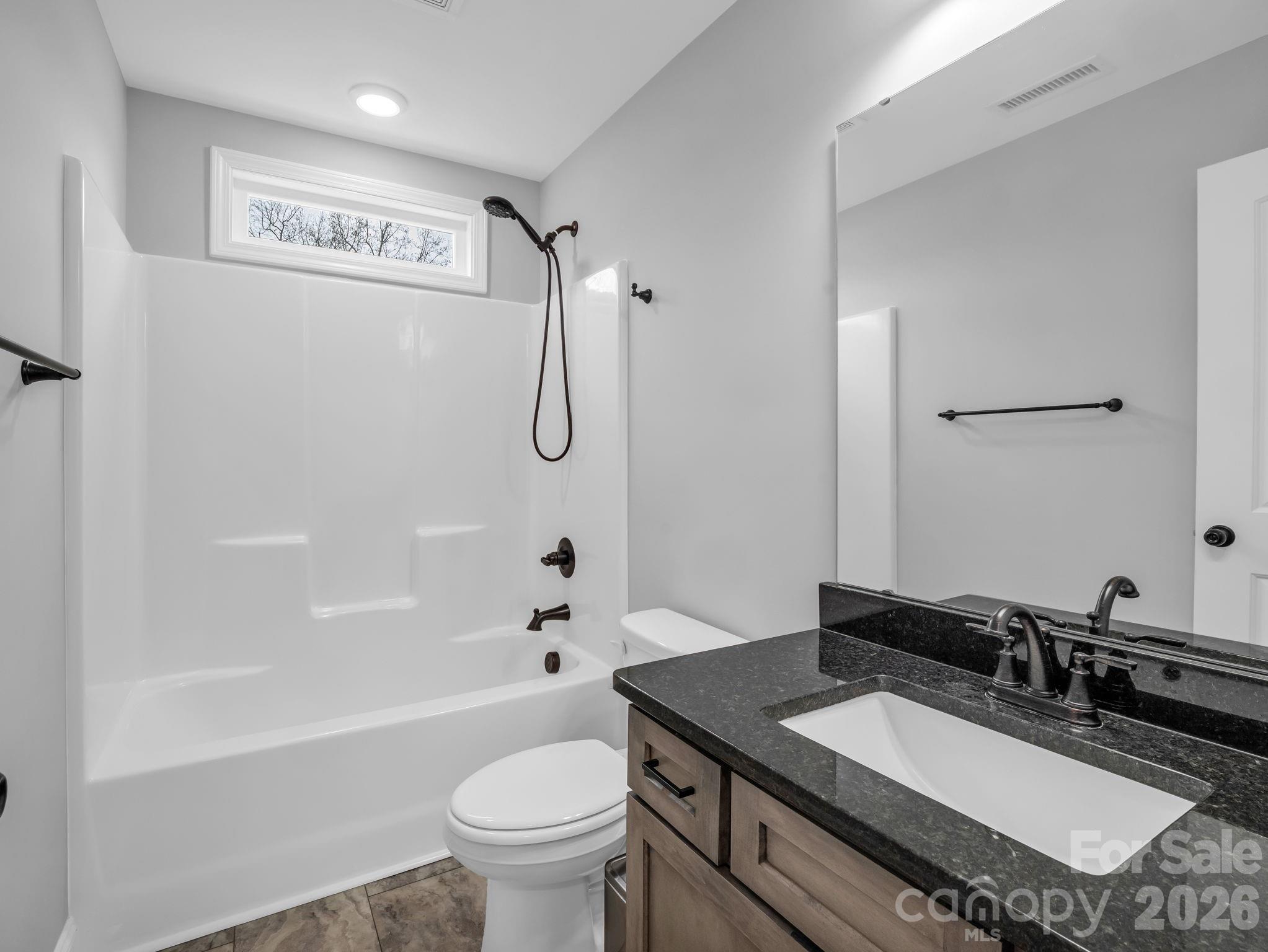 631 Mountain Parkway Mill Spring, NC 28756 - Photo 24 of 43 a bathroom with a granite countertop sink a toilet a mirror a bathtub and shower