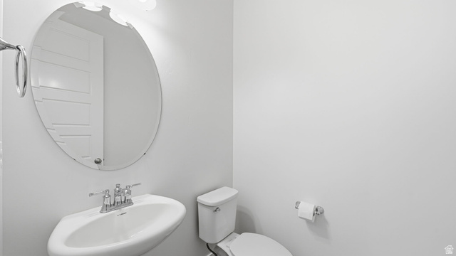6017 North Sheps Road, Unit C211 Eagle Mountain, UT 84005 - Photo 18 of 25 Pedestal sink with chrome faucet, oval mirror, wall-mounted light fixture, and white toilet, off mud room