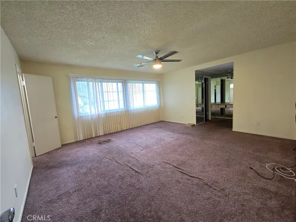 an empty room with windows and chandelier fan