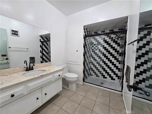 a bathroom with a granite countertop sink a toilet and shower