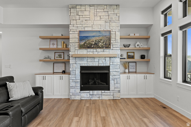 3111 South 1250 West Logan, UT 84321 - Photo 7 of 51 Stone-faced fireplace with a wood mantel, flanked by built-in cabinetry and floating wood shelving