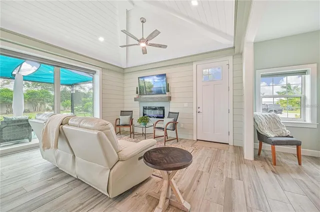 a living room with furniture a ceiling fan and a large window