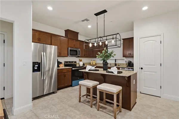 a kitchen with a refrigerator a stove a sink and chairs
