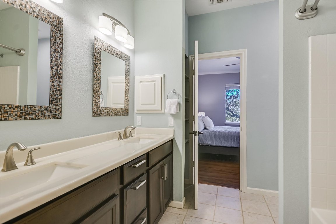7501 Shadowridge Run, Unit 110 Austin, TX 78749 - Photo 8 of 20 The en suite primary bath features dual sinks in a large vanity and built-in shelving for plenty of storage.