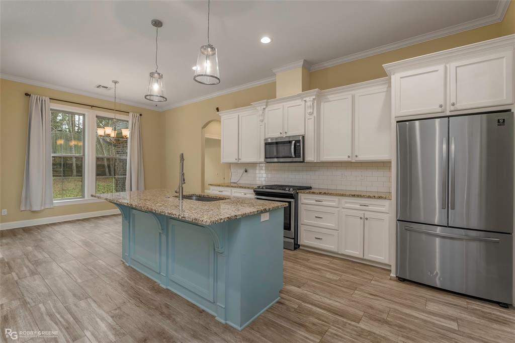352 Wood Springs Haughton, LA 71037 - Photo 4 of 34 a kitchen with kitchen island granite countertop a stove a sink a refrigerator and white cabinets with wooden floor