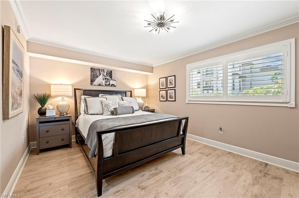 950 7th Avenue South, Unit 23 Naples, FL 34102 - Photo 11 of 40 a bedroom with a bed and a chandelier
