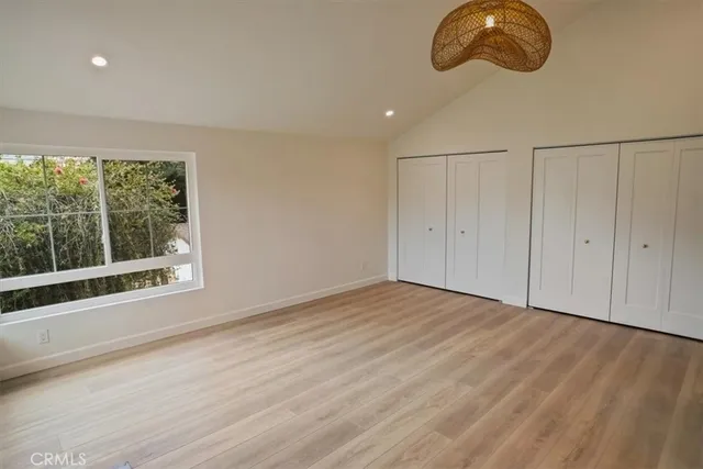 a view of an empty room with wooden floor and windows