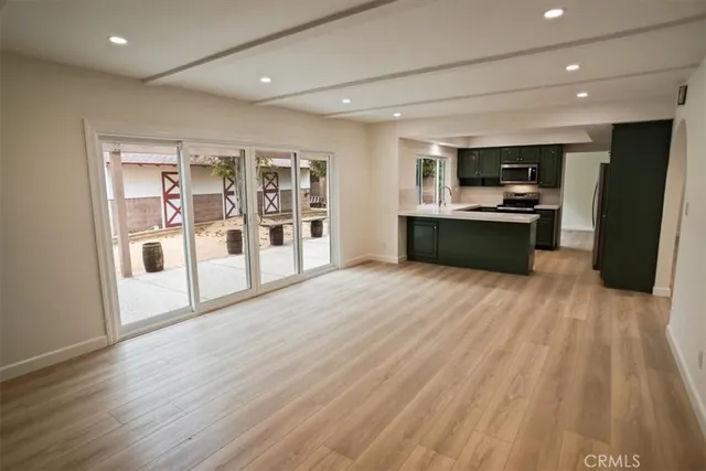 a large empty room with wooden floor and furniture