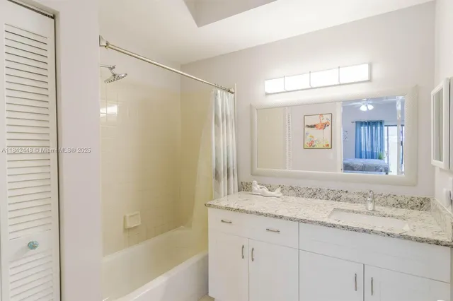a bathroom with a granite countertop sink mirror and a bathtub