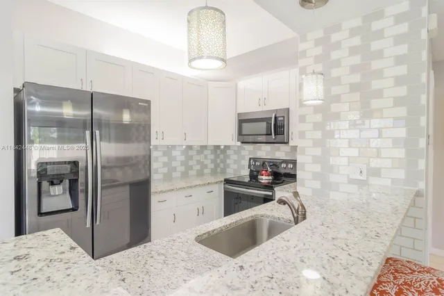 a kitchen with stainless steel appliances granite countertop a refrigerator a stove and a sink