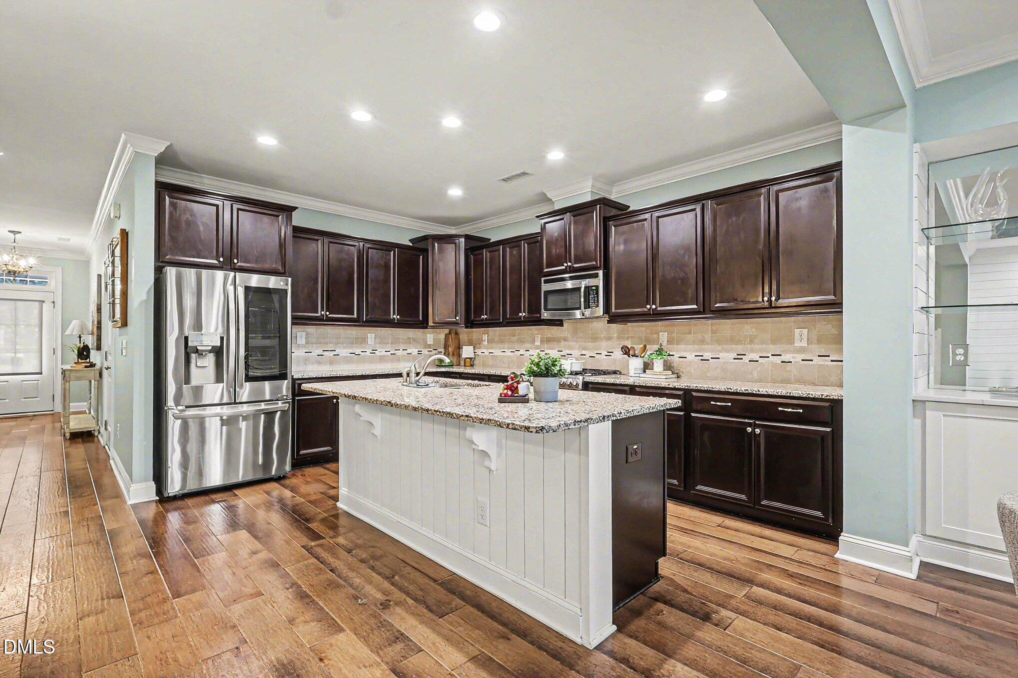 653 Fallon Grove Way Raleigh, NC 27608 - Photo 6 of 38 a kitchen with kitchen island granite countertop stainless steel appliances and sink