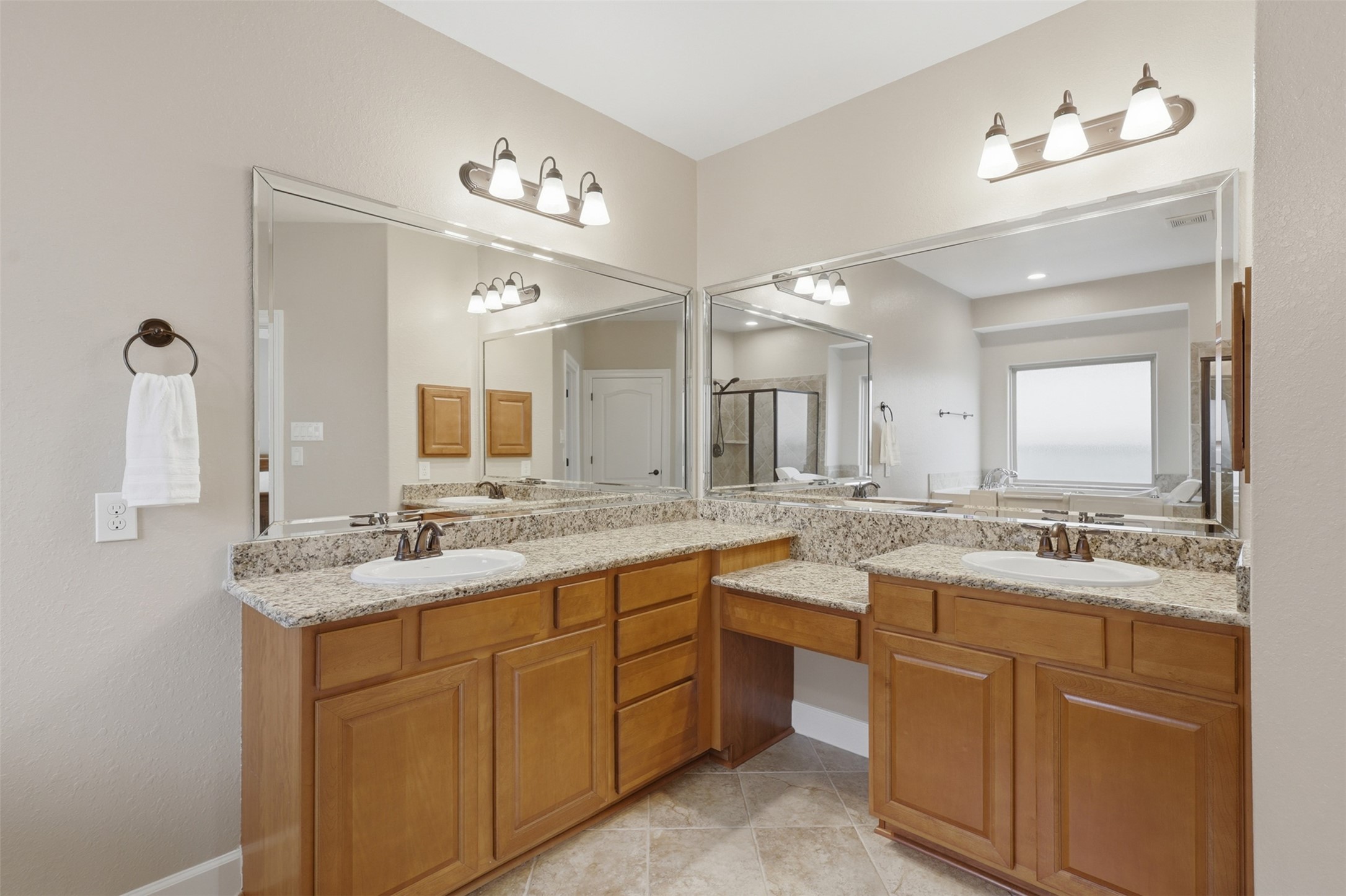 721 Rufina Street League City, TX 77573 - Photo 15 of 33 The spa-inspired ensuite bath offers exceptional functionality with dual granite-topped vanities, a dedicated sit-down station, large mirrors, and abundant cabinetry. Thoughtfully designed for everyday comfort, this elegant space provides generous storage and ample room to begin and end each day.