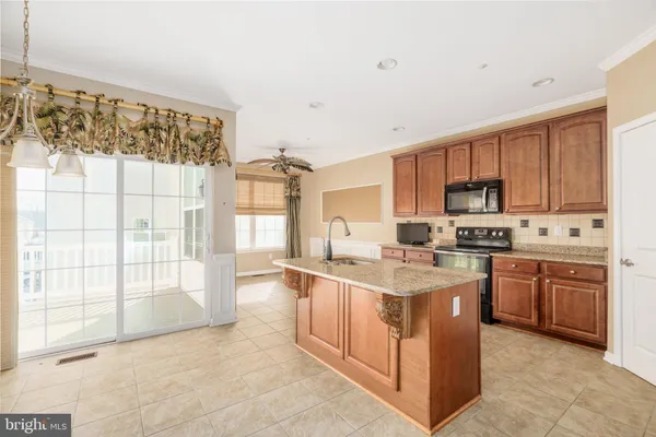 a kitchen with stainless steel appliances granite countertop a stove top oven a sink a dining table and chairs