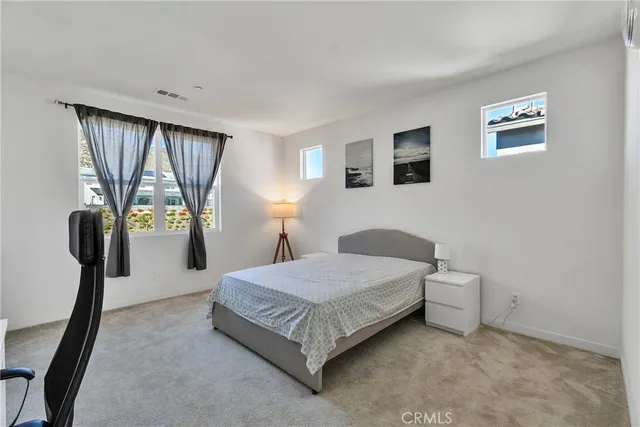 a bedroom with a bed lamp and a large window