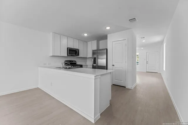 a kitchen with stainless steel appliances granite countertop a refrigerator sink and white cabinets