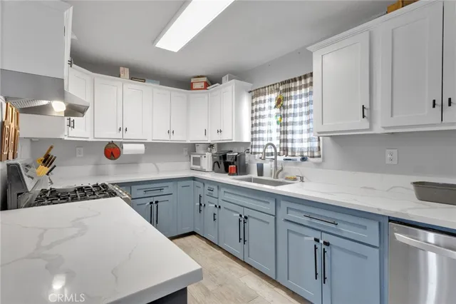 a kitchen with stainless steel appliances granite countertop a sink dishwasher a stove and white cabinets with wooden floor