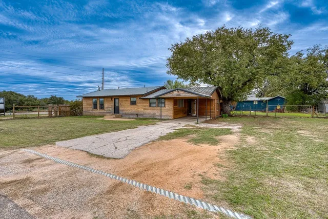 a view of a house with backyard and a tree