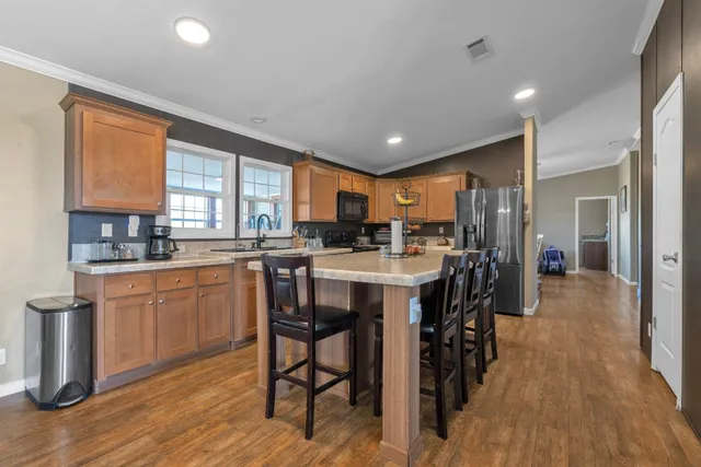 a kitchen with stainless steel appliances kitchen island granite countertop a table chairs cabinets and wooden floor