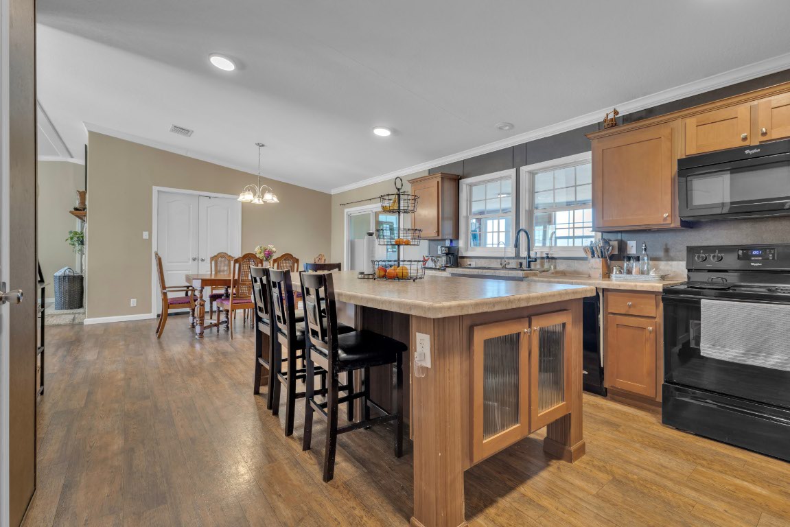 401 High Ridge Meadows Drive Gonzales, TX 78629 - Photo 16 of 31 a kitchen with stainless steel appliances granite countertop a stove top oven a sink a dining table and chairs with wooden floor