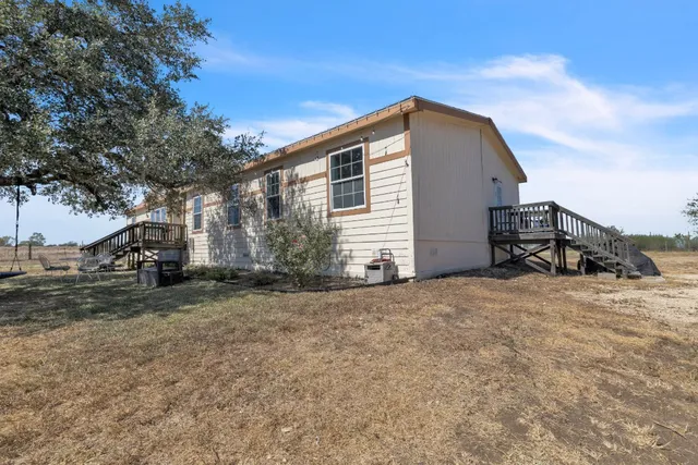a backyard of a house with wooden fence and a large tree