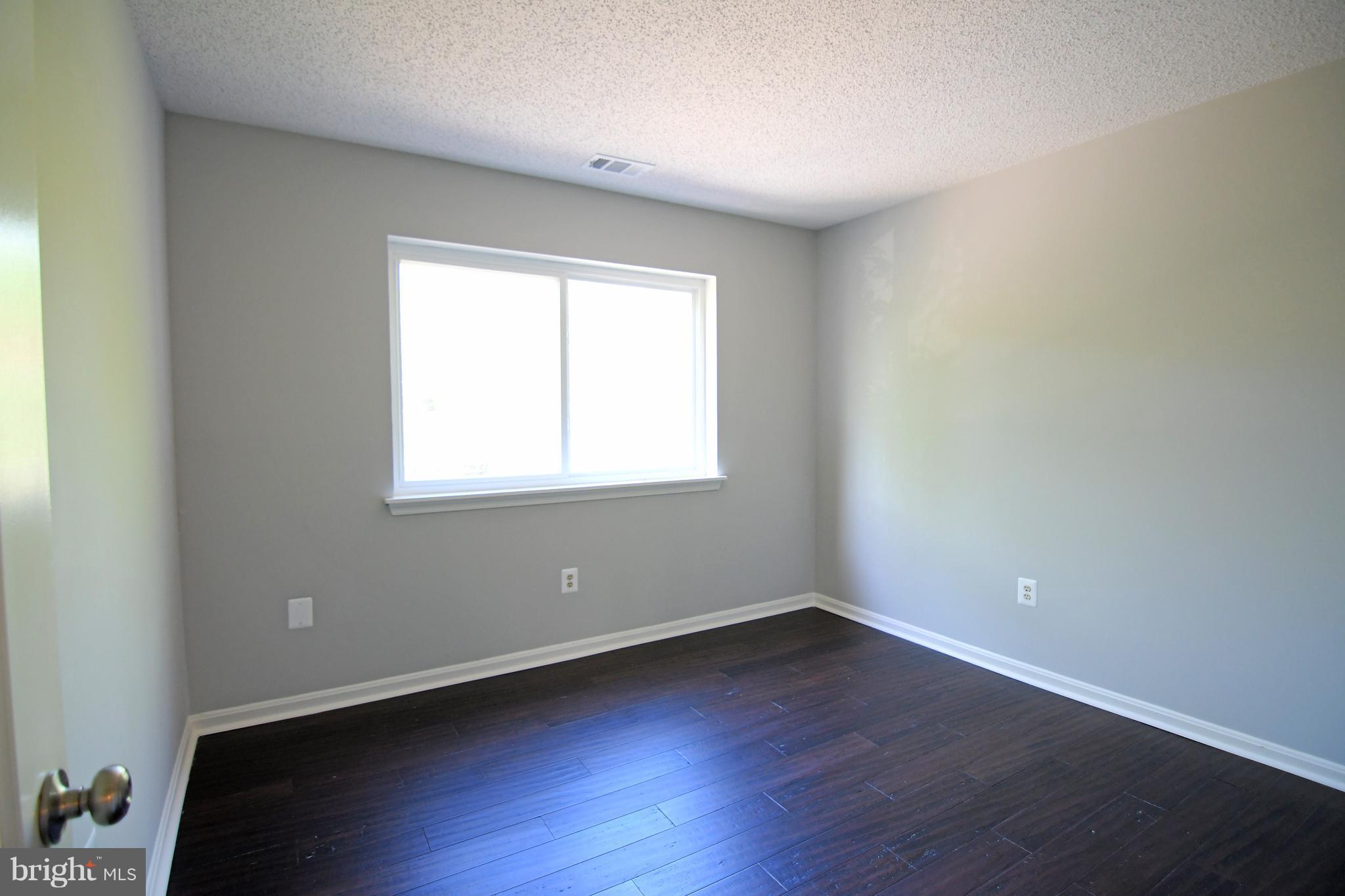 10803 Amherst Avenue, Unit F Silver Spring, MD 20902 - Photo 7 of 23 an empty room with wooden floor and windows