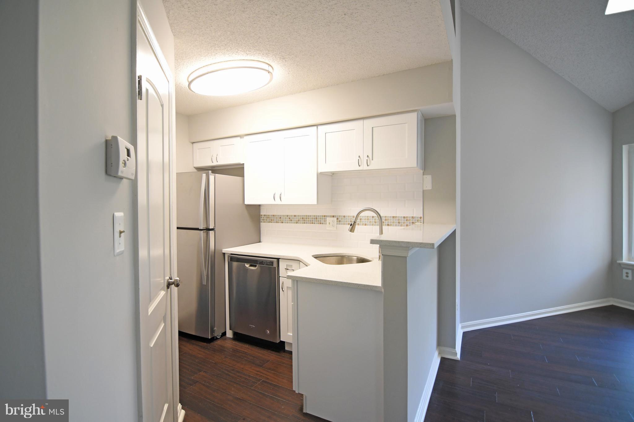 10803 Amherst Avenue, Unit F Silver Spring, MD 20902 - Photo 10 of 23 a kitchen with a sink cabinets stainless steel appliances and wooden floor