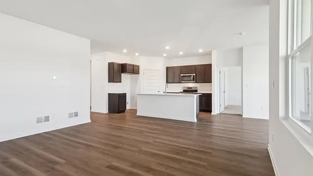 a kitchen with granite countertop a stove top oven a sink dishwasher and a microwave with wooden floor
