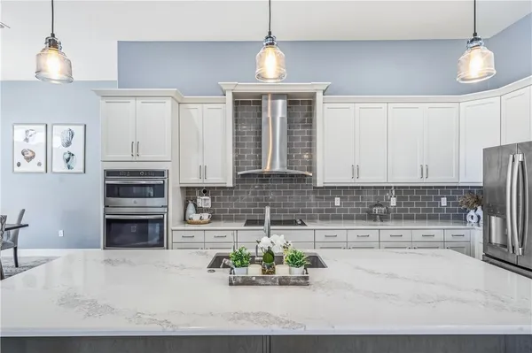 a kitchen with kitchen island a counter top space a sink stainless steel appliances and cabinets