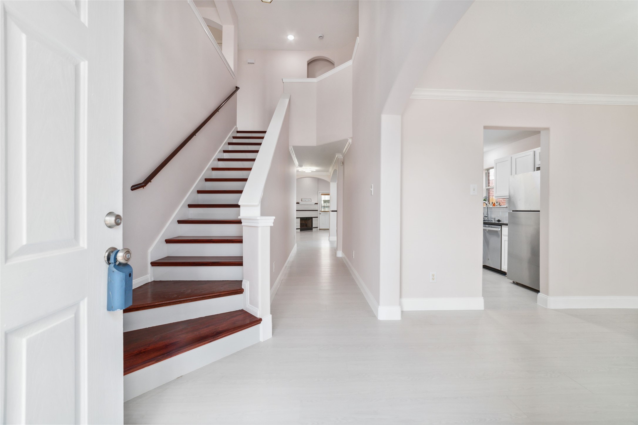 8330 Malin Court Houston, TX 77083 - Photo 3 of 21 Welcome to a bright and airy home featuring a spacious entryway with elegant wooden stairs leading to the upper floor. The modern kitchen with stainless steel appliances is visible to the right, offering an inviting and functional layout.