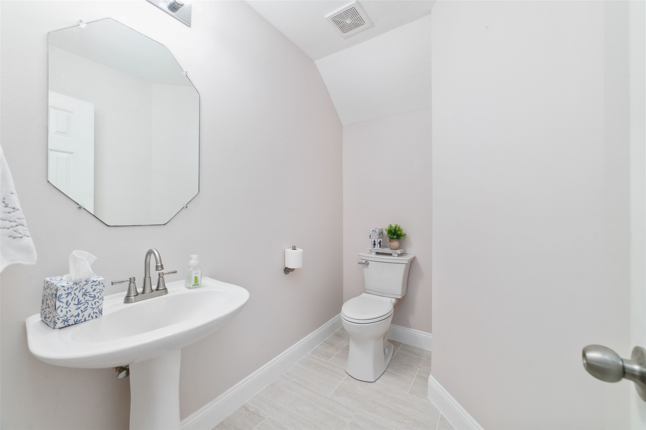 8330 Malin Court Houston, TX 77083 - Photo 7 of 21 This is a bright, modern half-bathroom featuring a pedestal sink, octagonal mirror. The walls are painted a soft neutral color.