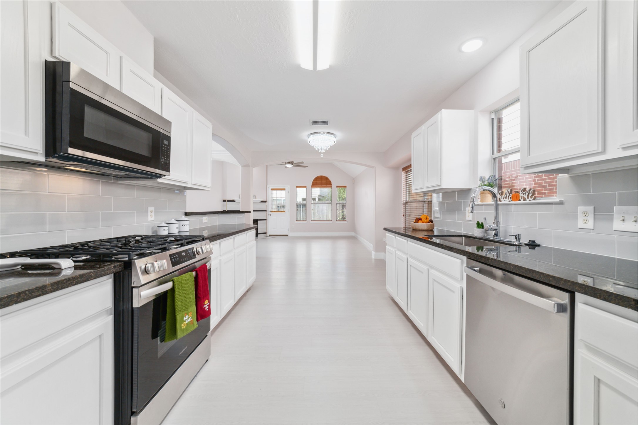 8330 Malin Court Houston, TX 77083 - Photo 8 of 21 This photo showcases a spacious, modern kitchen with sleek white cabinetry, dark countertops, and stainless steel appliances.