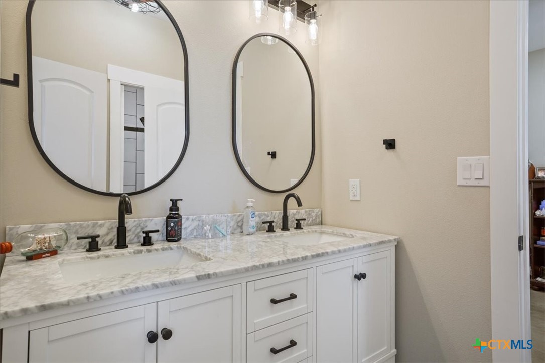 1490 Dos Hermanas Road Salado, TX 76571 - Photo 26 of 43 a bathroom with a granite countertop double vanity sinks and a mirror