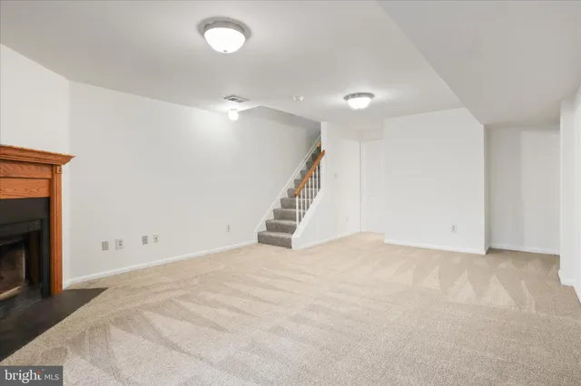 a view of an empty room with stairs and a fireplace