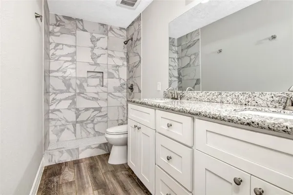 a bathroom with a granite countertop toilet sink and a shower