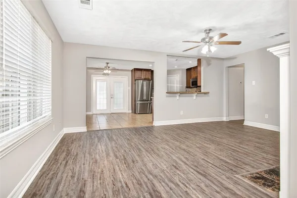 a view of empty room with wooden floor and fan