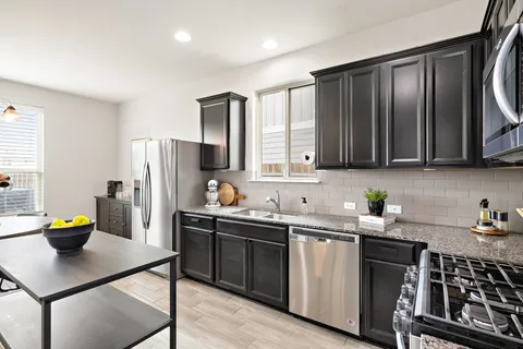 a kitchen with stainless steel appliances a sink a stove a refrigerator cabinets and a window