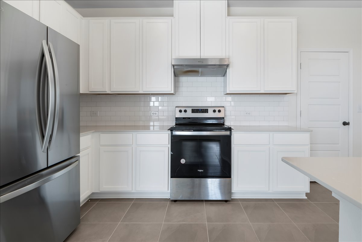18501 Spotted Eagle Lane Elgin, TX 78621 - Photo 6 of 40 A well-equipped kitchen features crisp white cabinetry, durable tile flooring, and stainless steel appliances.