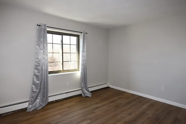 an empty room with wooden floor and window