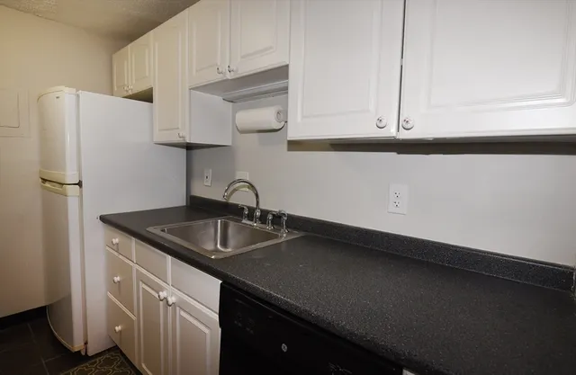 a kitchen with granite countertop a sink a refrigerator and cabinets