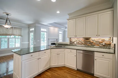 a kitchen with granite countertop white cabinets and white stainless steel appliances