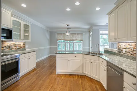 a kitchen with granite countertop a stove a sink and a wooden floors