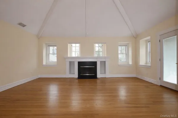 an empty room with windows a fireplace and wooden floor