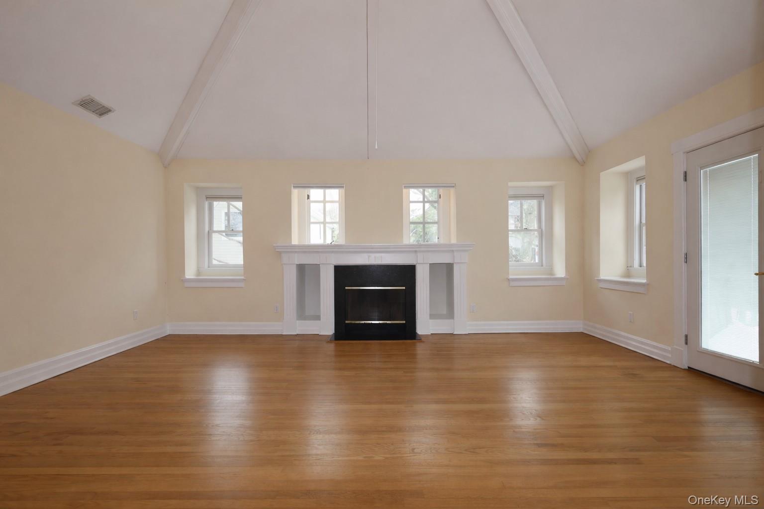 16 Clinton Avenue Dobbs Ferry, NY 10522 - Photo 14 of 26 an empty room with windows a fireplace and wooden floor