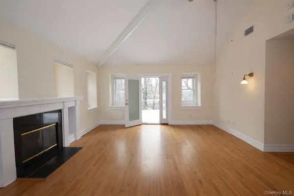 an empty room with wooden floor fireplace and windows