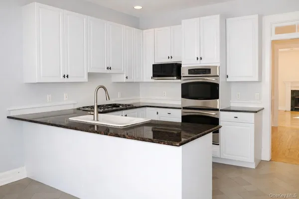 a kitchen with granite countertop white cabinets and a sink
